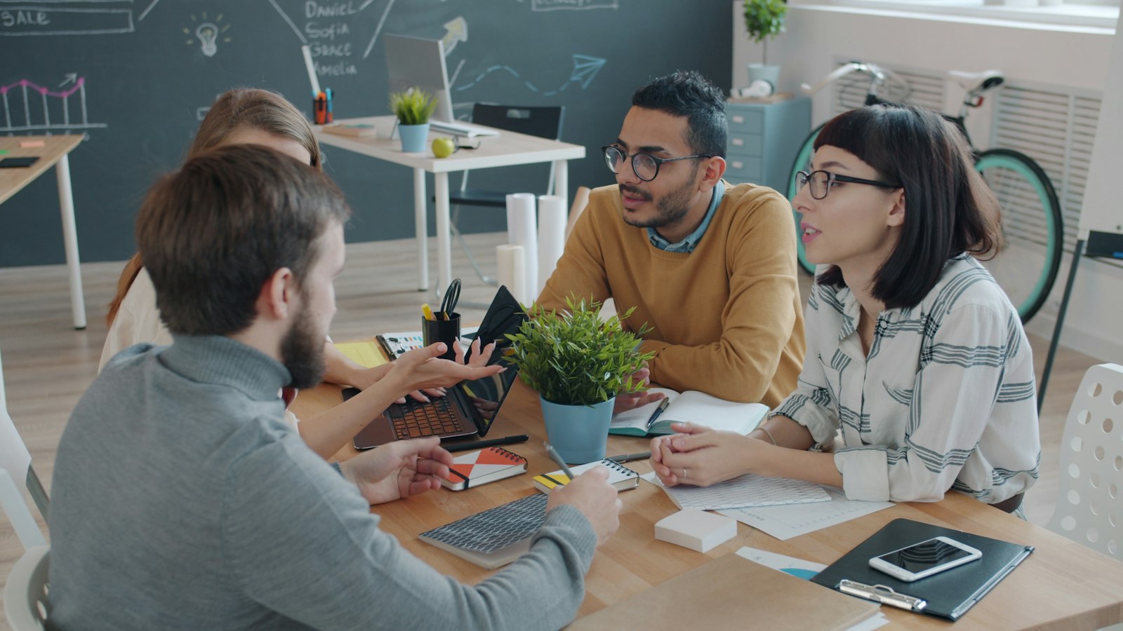 Four coworkers discussing ideas together around a table in an office